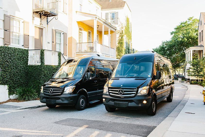 Two black vans are parked on the side of a street.