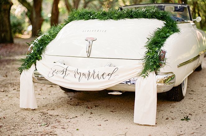 A white car with a just married sign on the back of it.