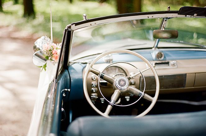 A close up of the steering wheel and dashboard of an old car.