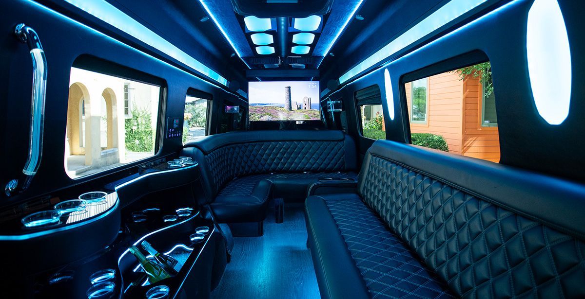 The inside of a limousine with a flat screen tv on the ceiling.