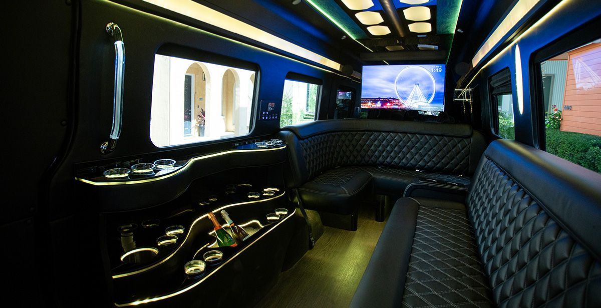 The inside of a limousine with a couch and a television.