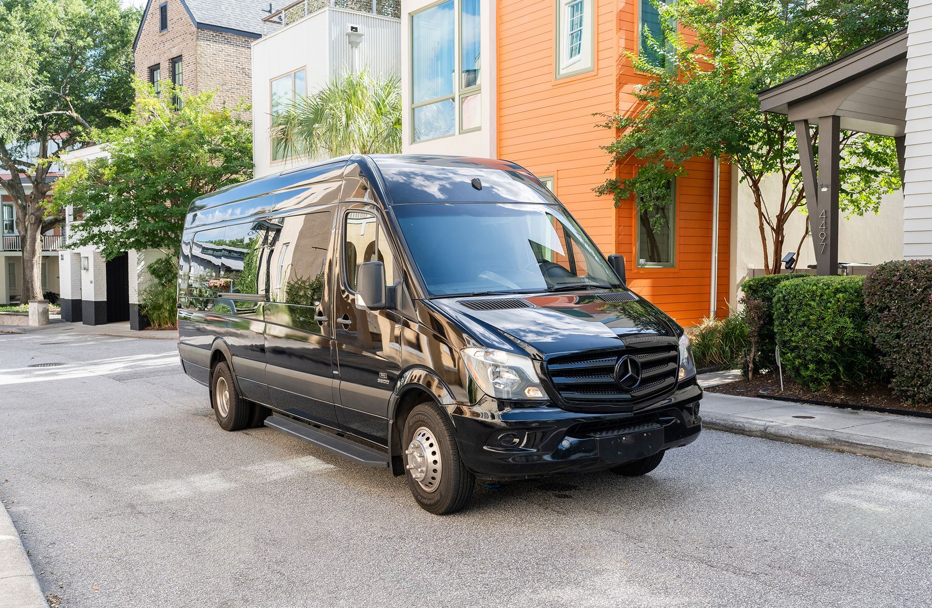 A black van is parked on the side of the road in front of a colorful building.