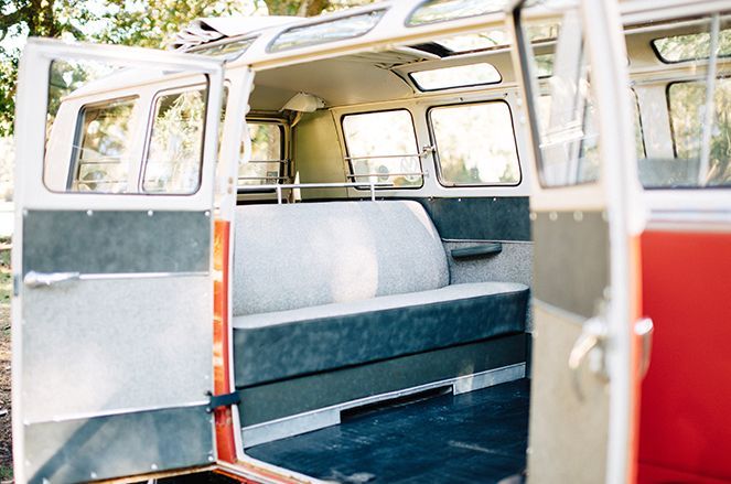 The inside of a van with the doors open and a couch in the back.