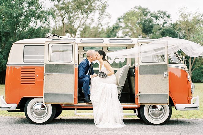 A bride and groom are kissing in a red and white van.