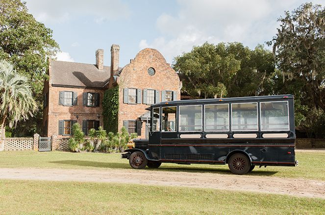 A black bus is parked in front of a large brick building.