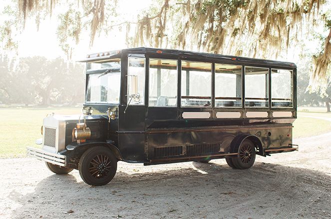 A black bus is parked on the side of a dirt road.