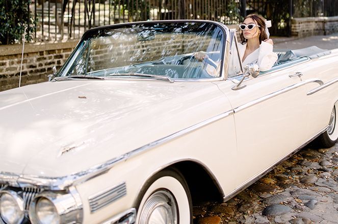 A woman is sitting in a white convertible car.