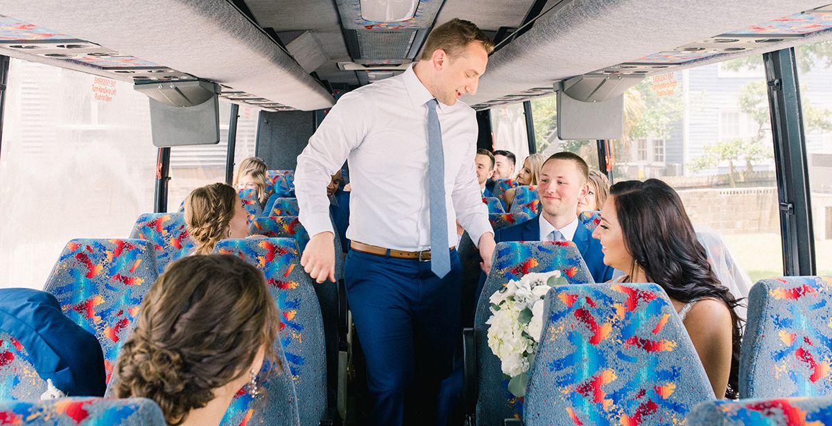 A bride and groom are walking down the aisle of a wedding bus.