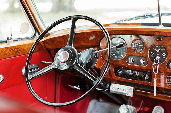 A close up of the steering wheel and dashboard of an old car.