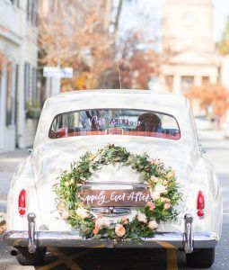 A white car with a wreath on the back of it and a sign that says `` happily ever after ''.