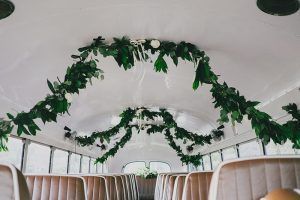 The inside of a bus decorated with flowers and greenery for a wedding ceremony.