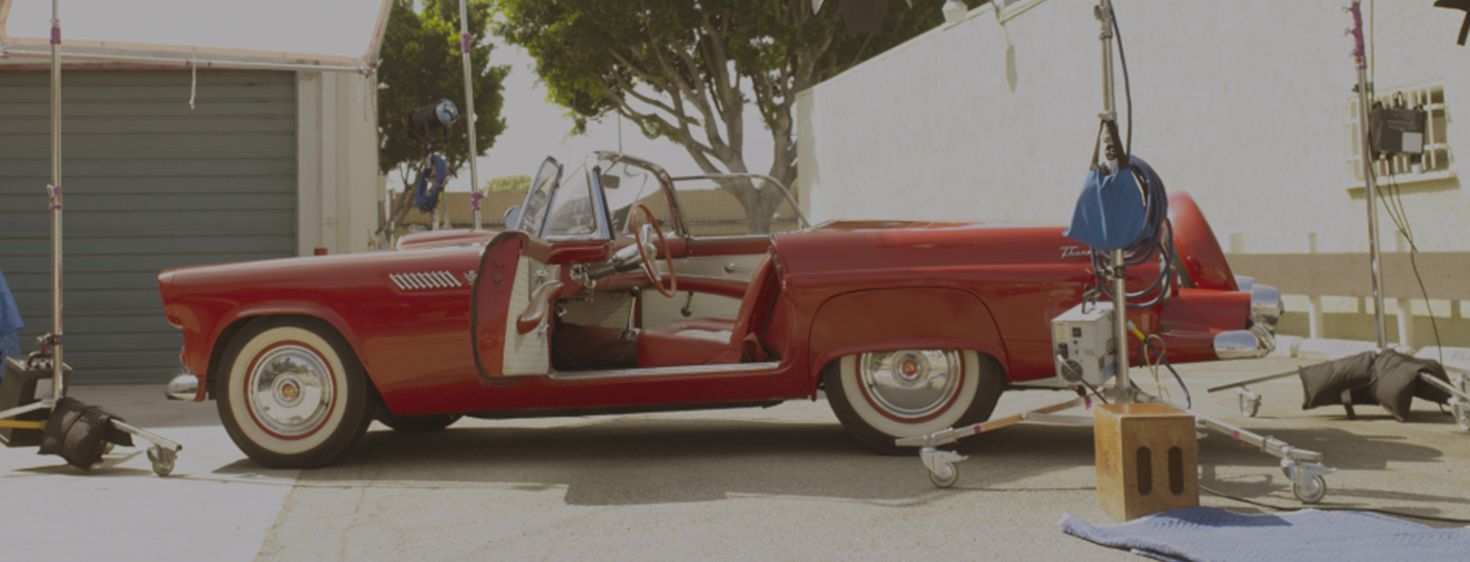 A red car is parked in front of a garage.