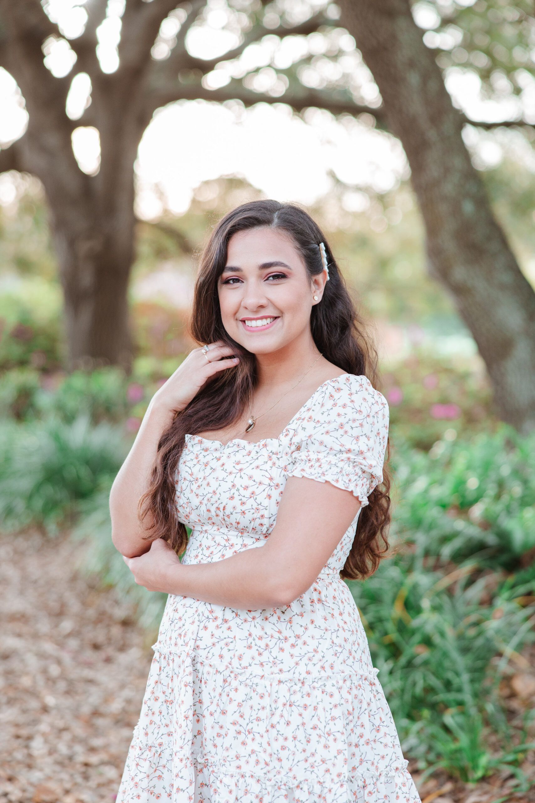 A woman in a white dress is posing for a picture in a park.