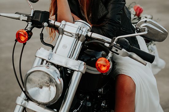 A woman in a wedding dress is riding a motorcycle.