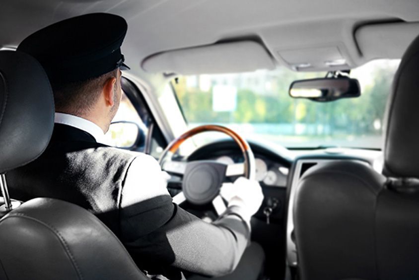 A man is driving a car with a wooden steering wheel.