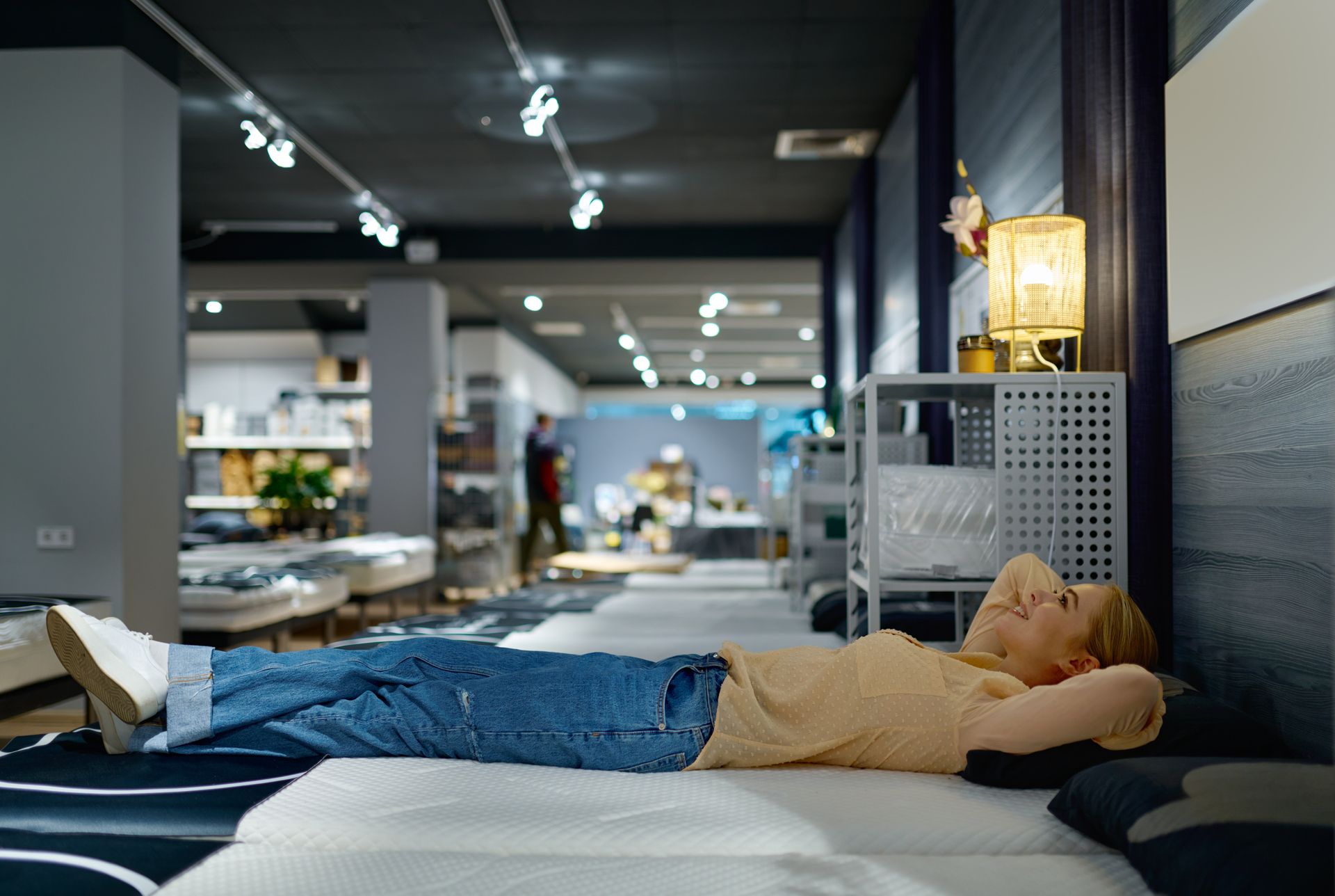 Woman choosing bed mattress in furniture store.