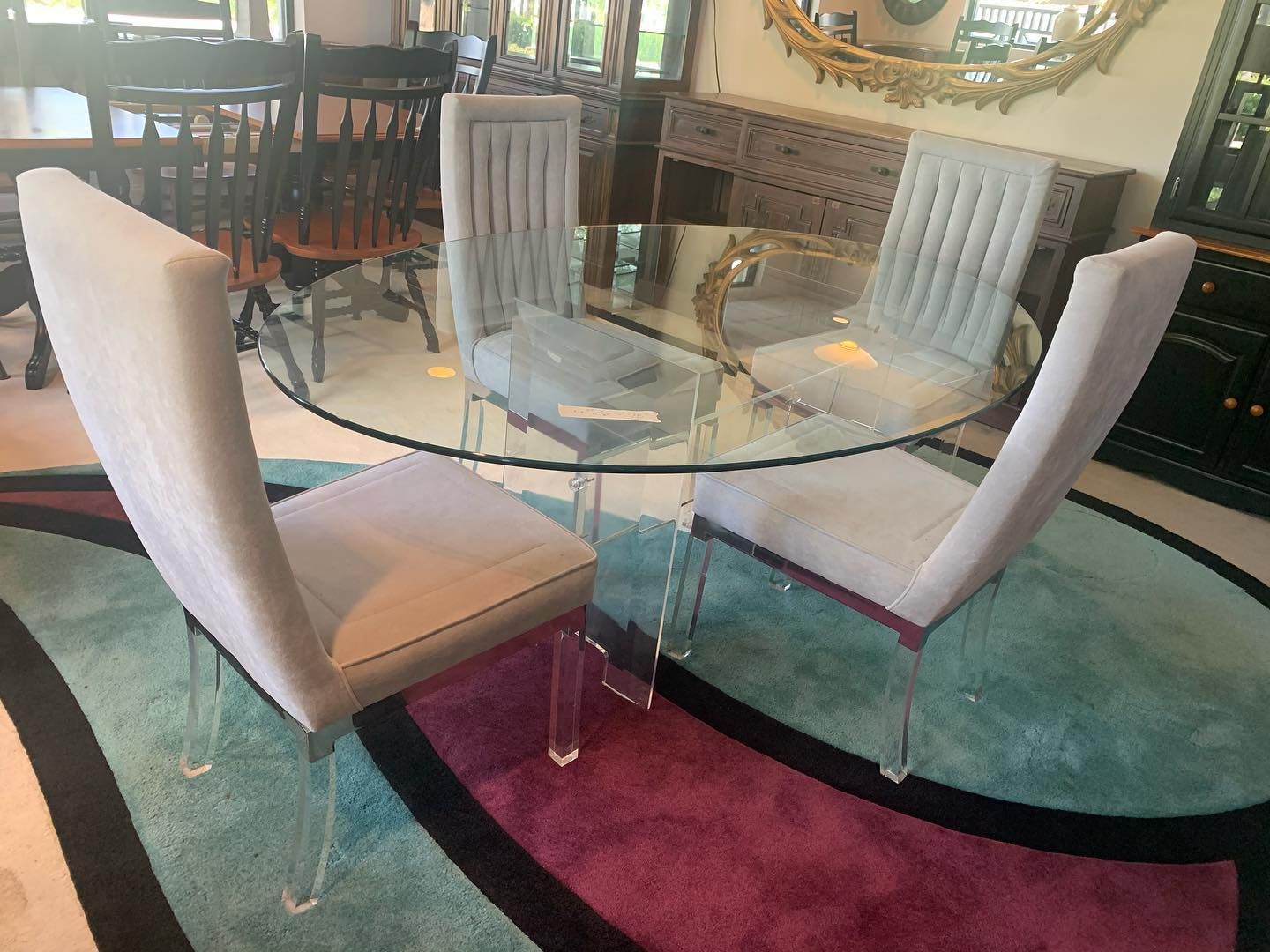 A dining room with a glass table and chairs on a rug.