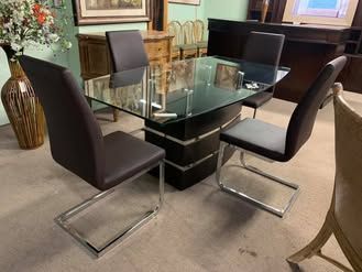 A dining room table and chairs in a room with a vase of flowers.