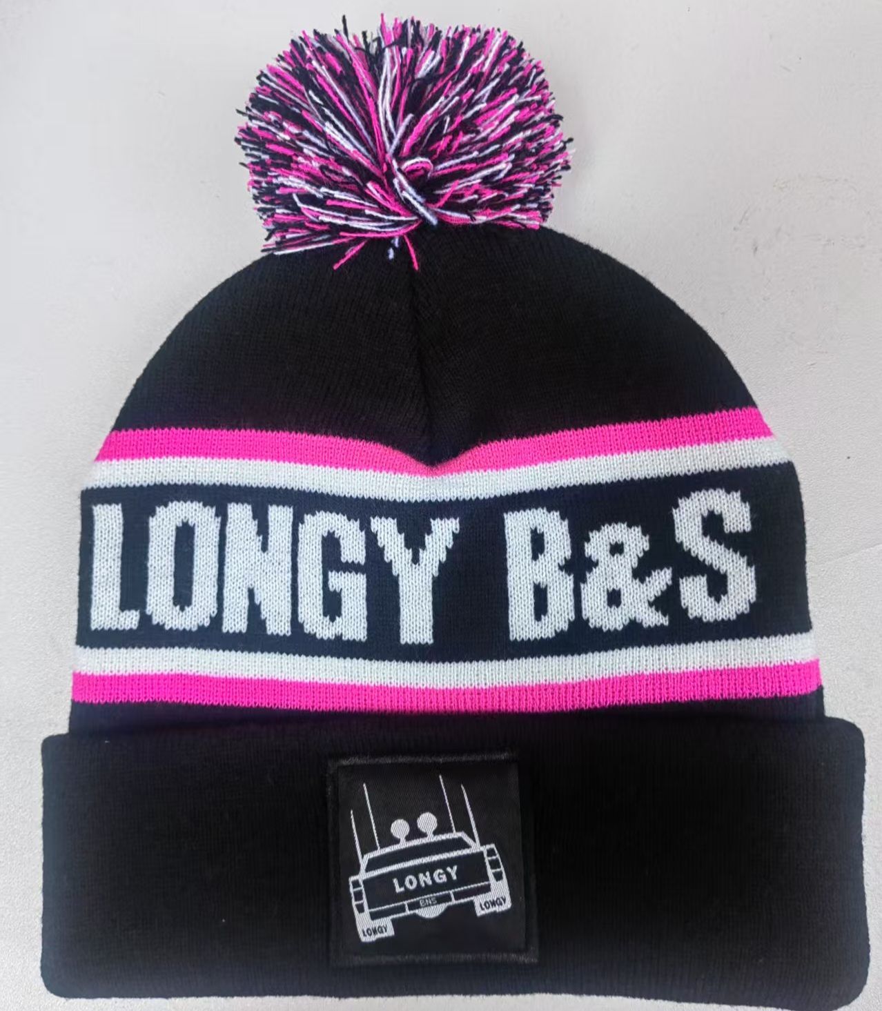 A black and pink longy b & s beanie with a pink pom pom
