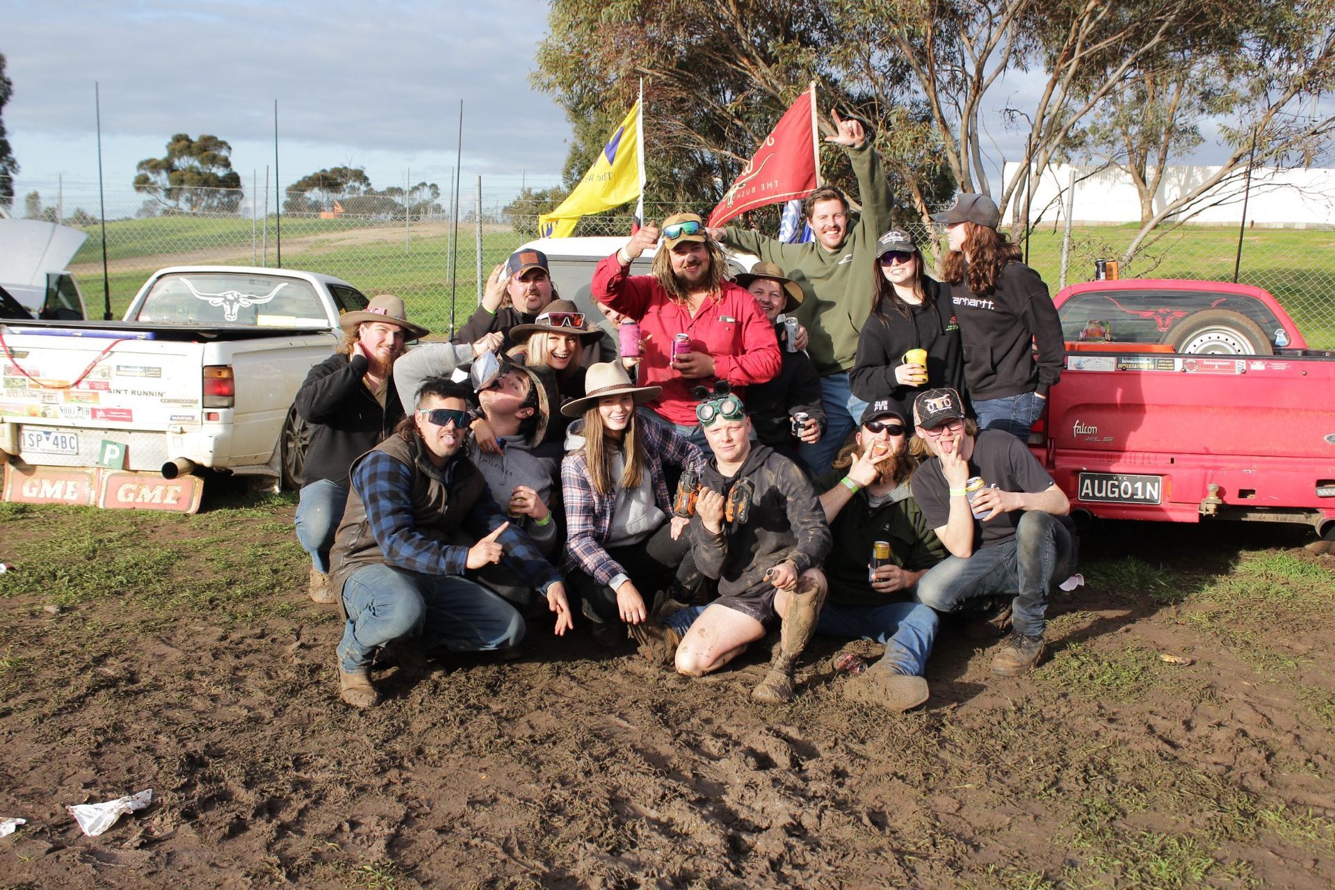 A group of people posing for a picture in a muddy field