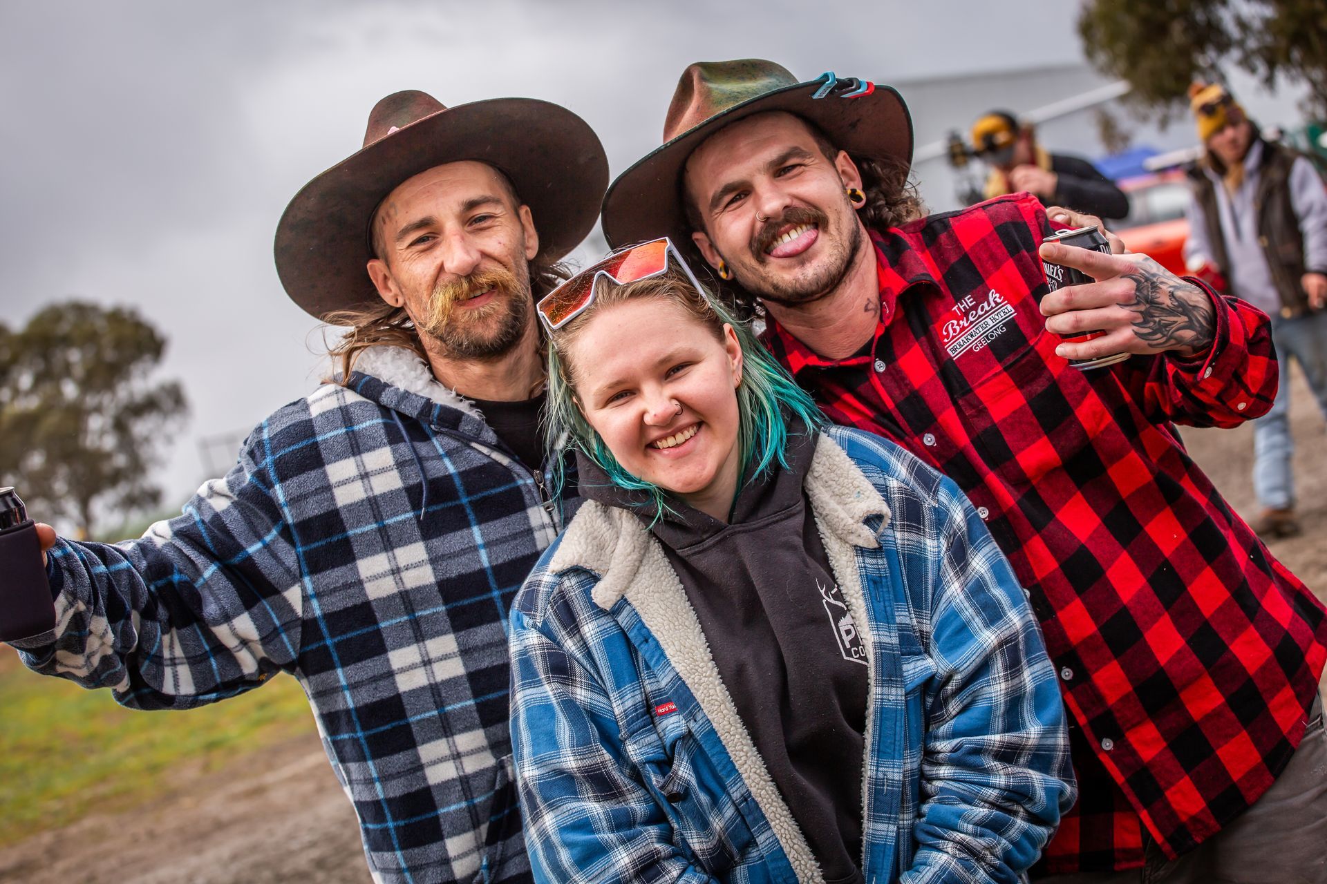 Three people posing for a picture with one wearing a plaid shirt