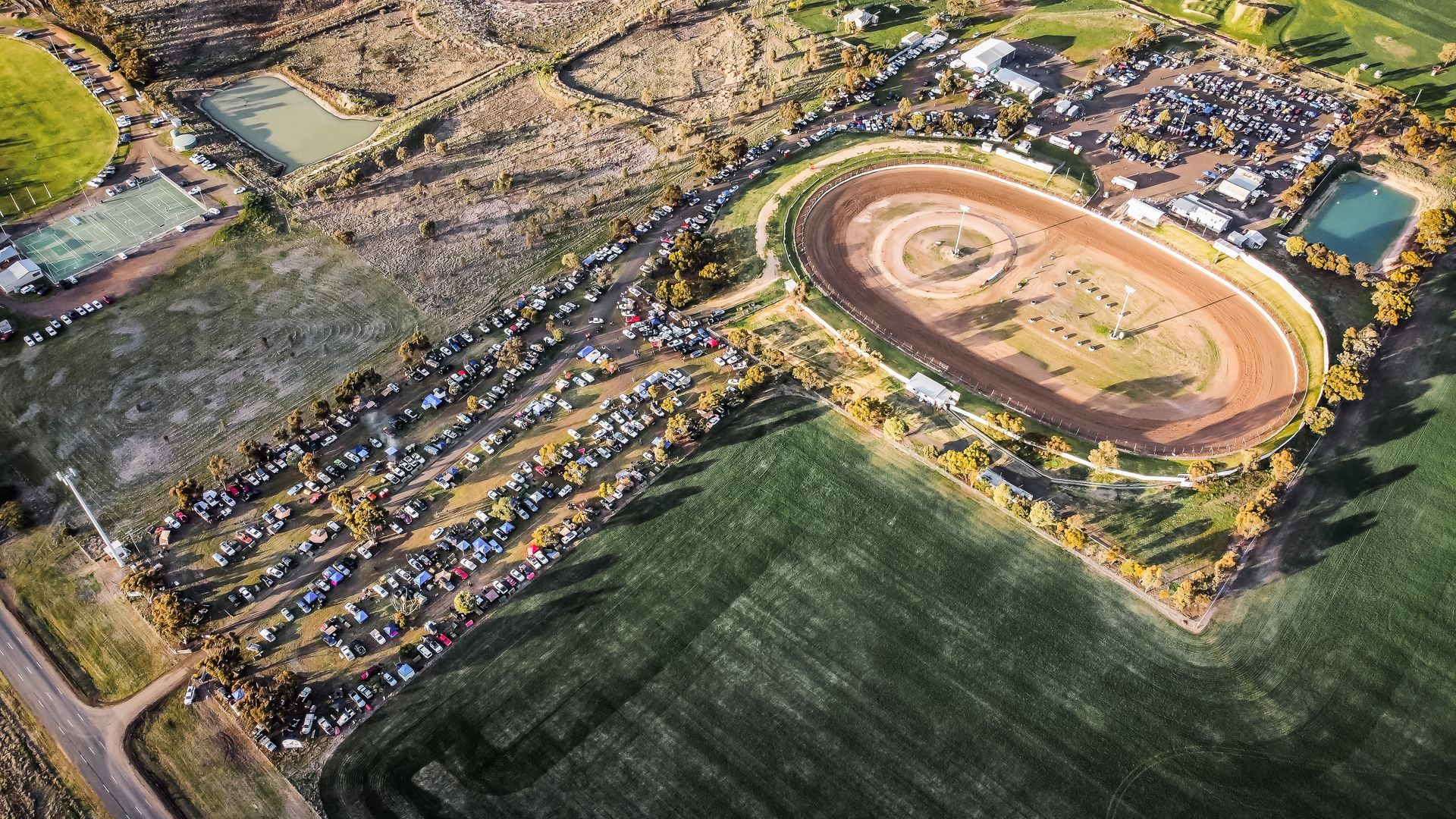 An aerial view of a race track with a lot of cars parked in front of it