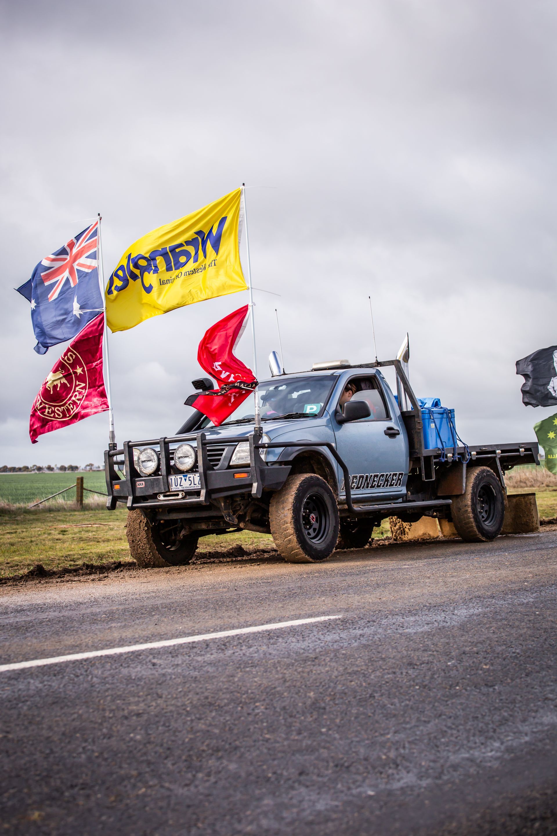 A truck with a yellow flag that says aussie on it