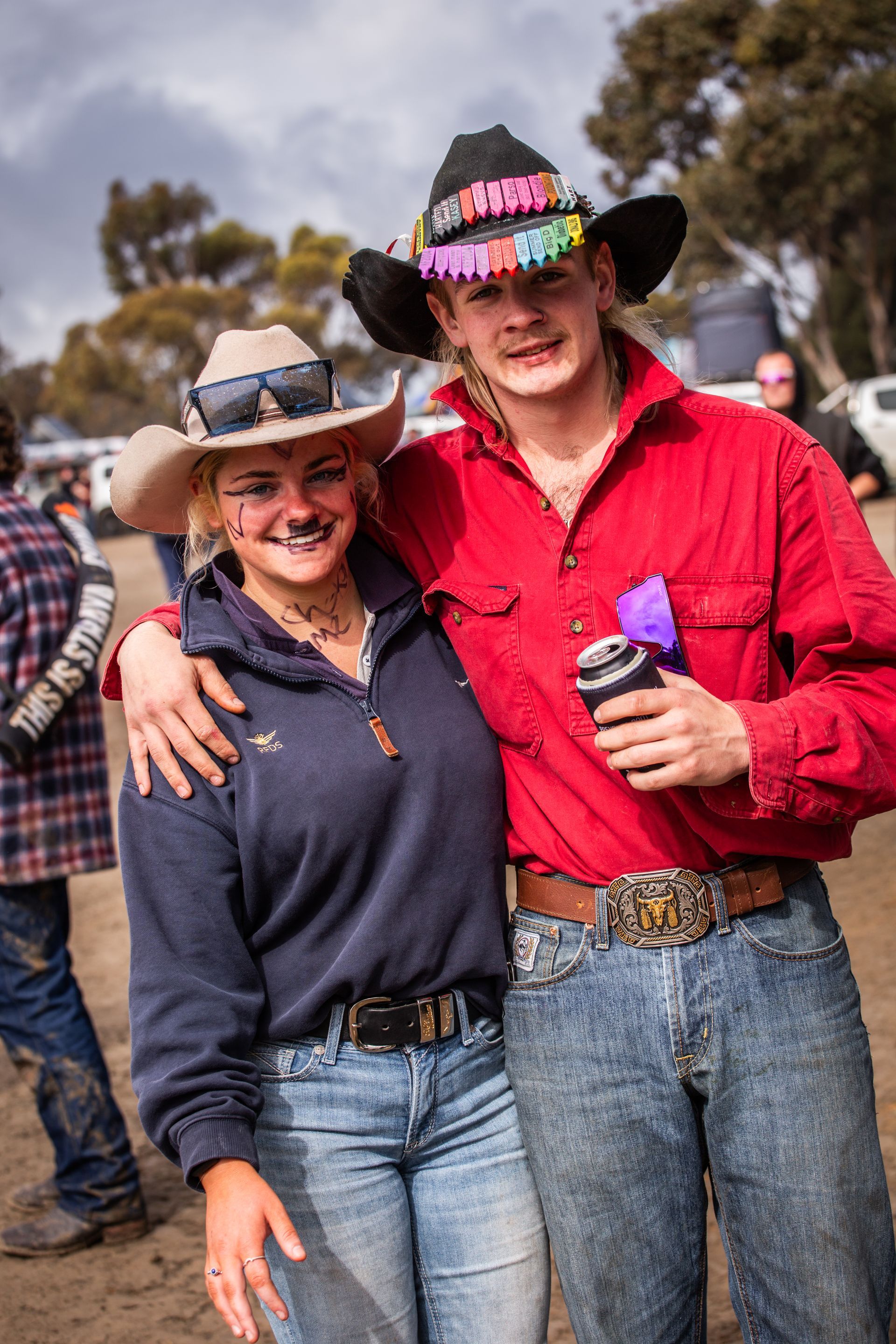 A man and a woman posing for a picture with one wearing a cowboy hat