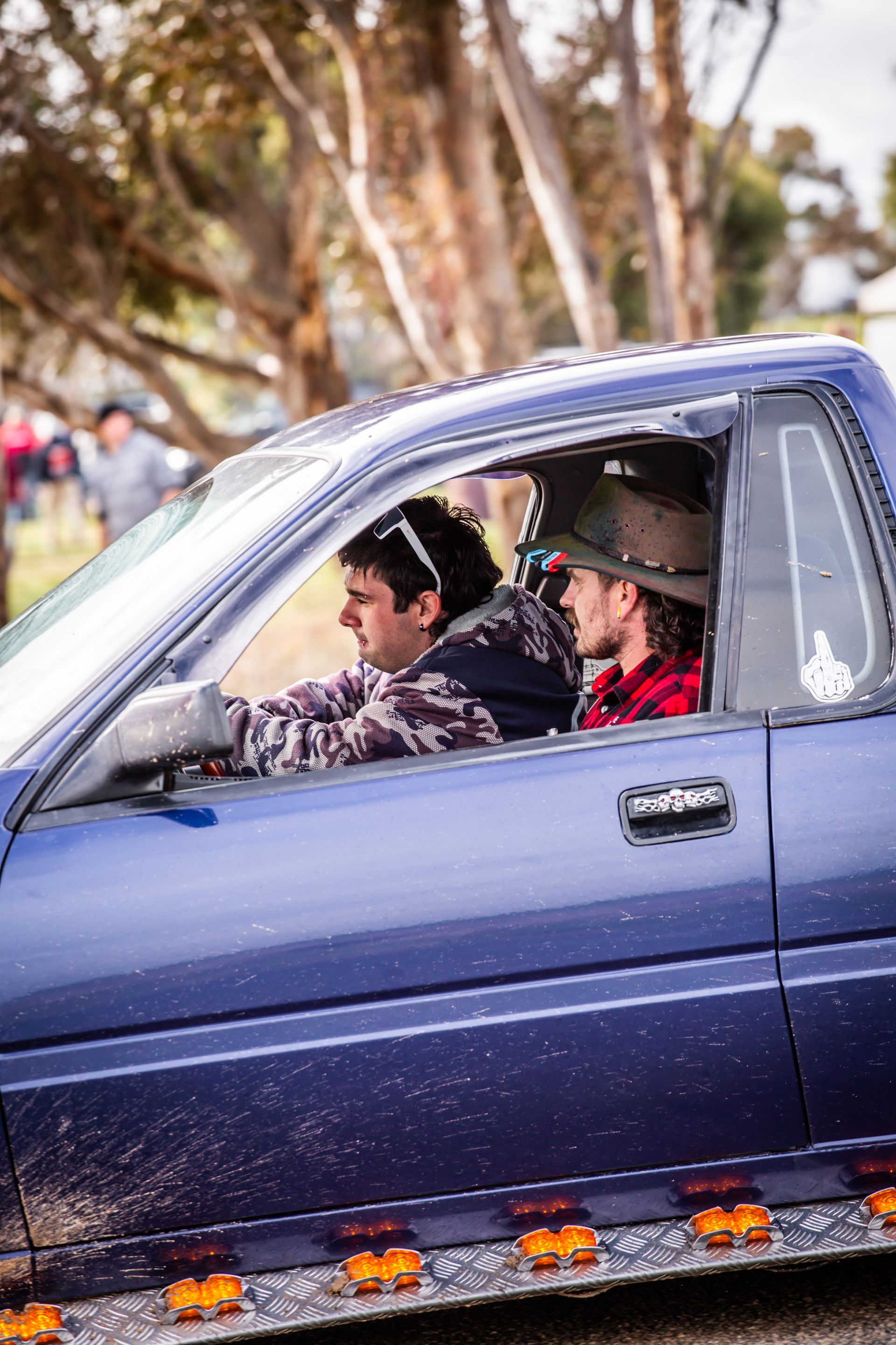 A man in a cowboy hat is driving a blue truck