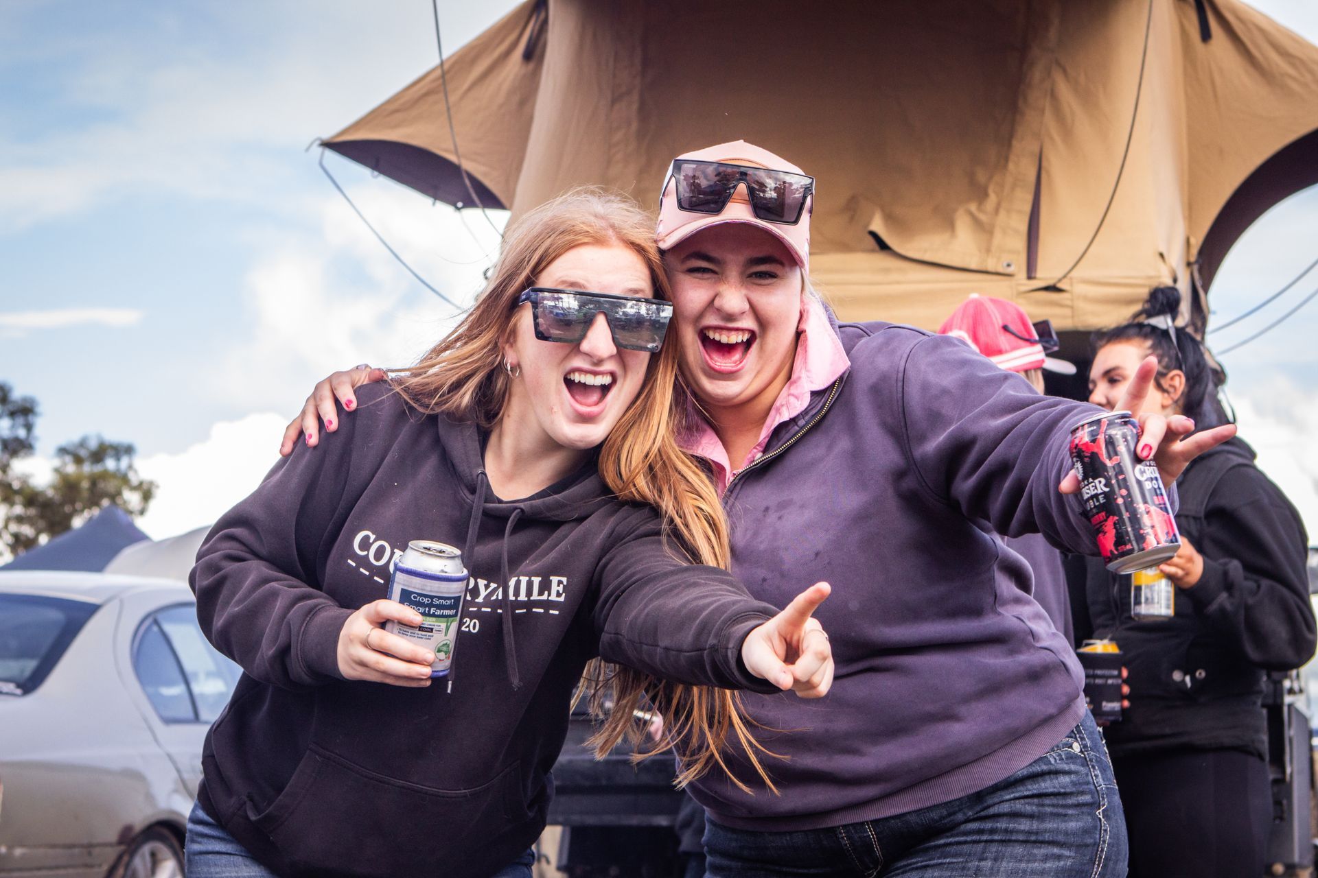 Two women are posing for a picture with a tent in the background