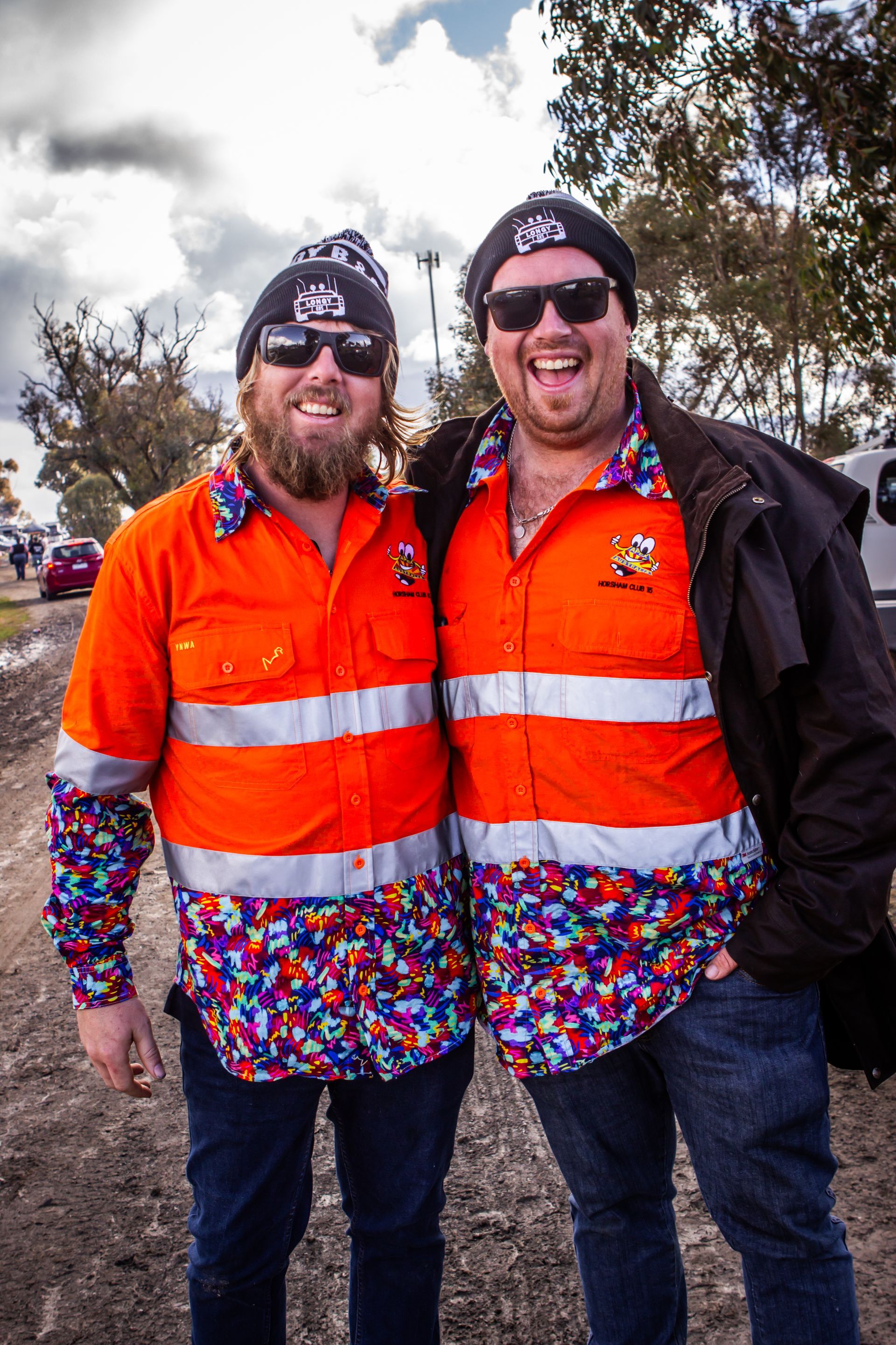 Two men posing for a picture with one wearing a hat with the letter k on it