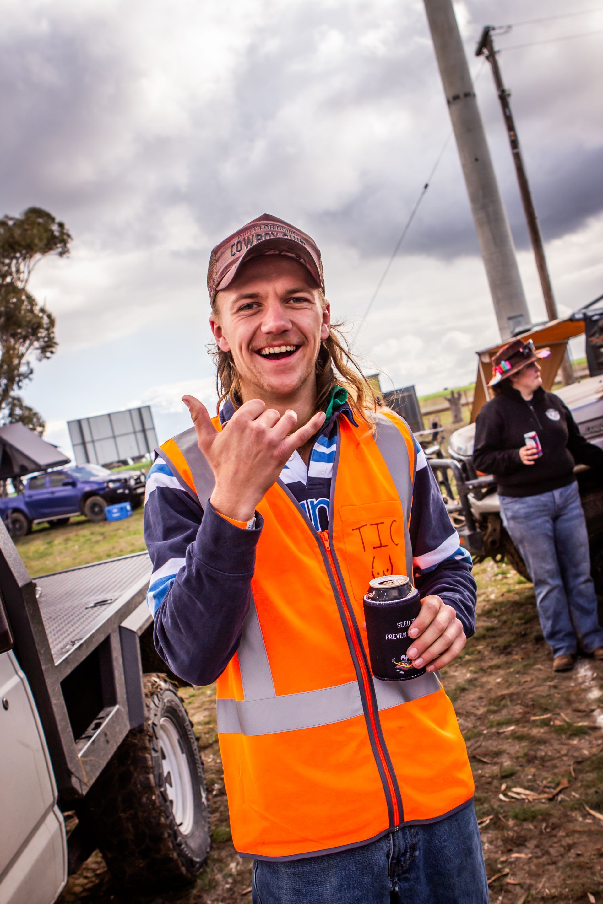 A man wearing an orange vest holds a can of soda
