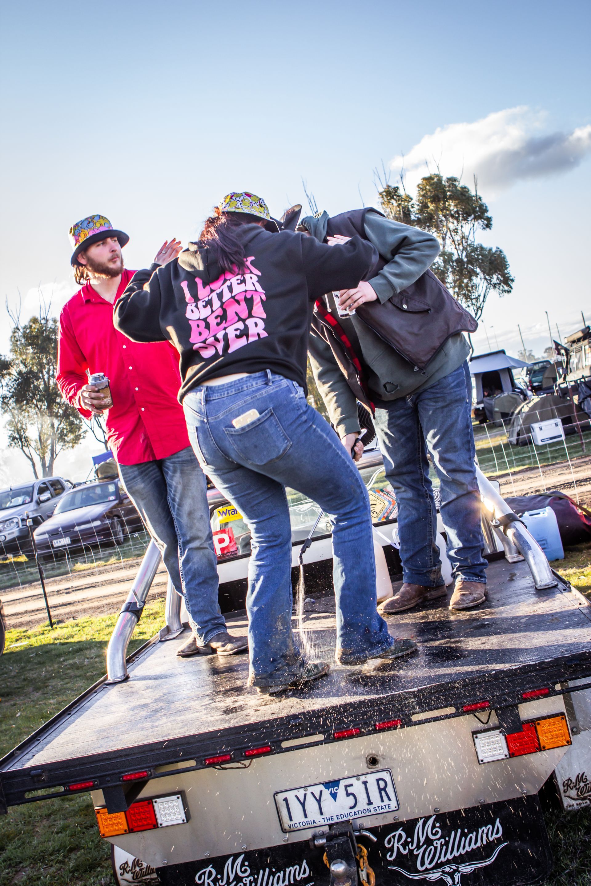 A man in a red shirt is standing on the back of a truck