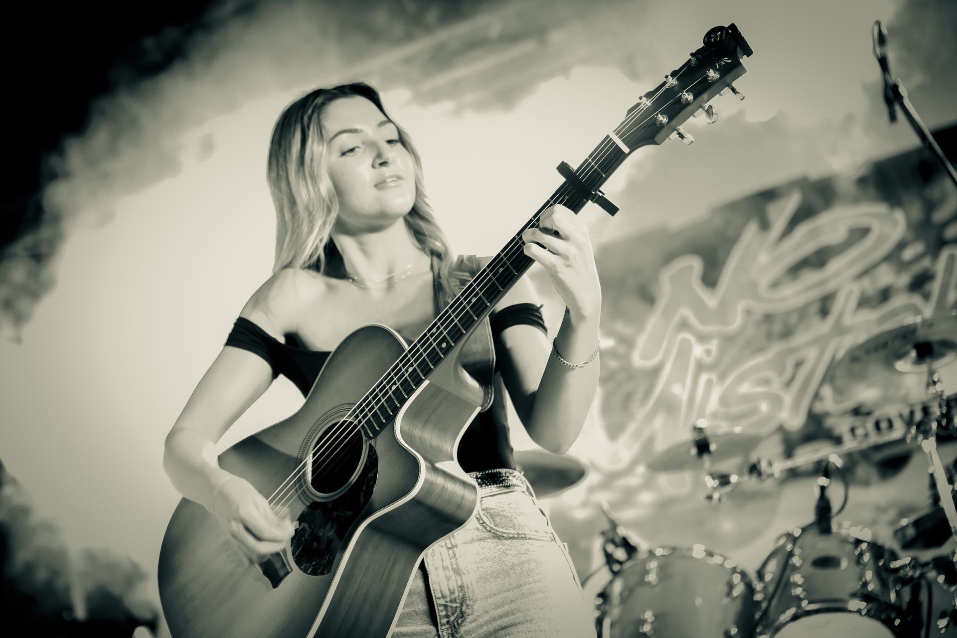A woman is playing an acoustic guitar on stage