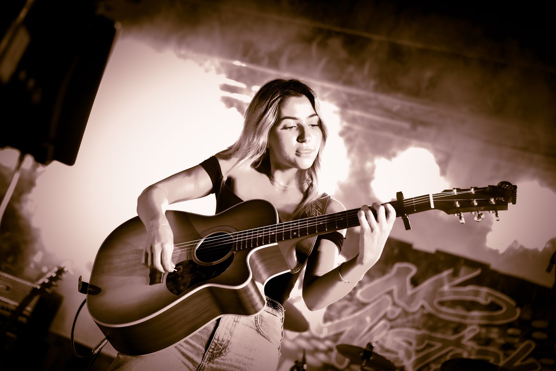 A woman is playing an acoustic guitar with her eyes closed