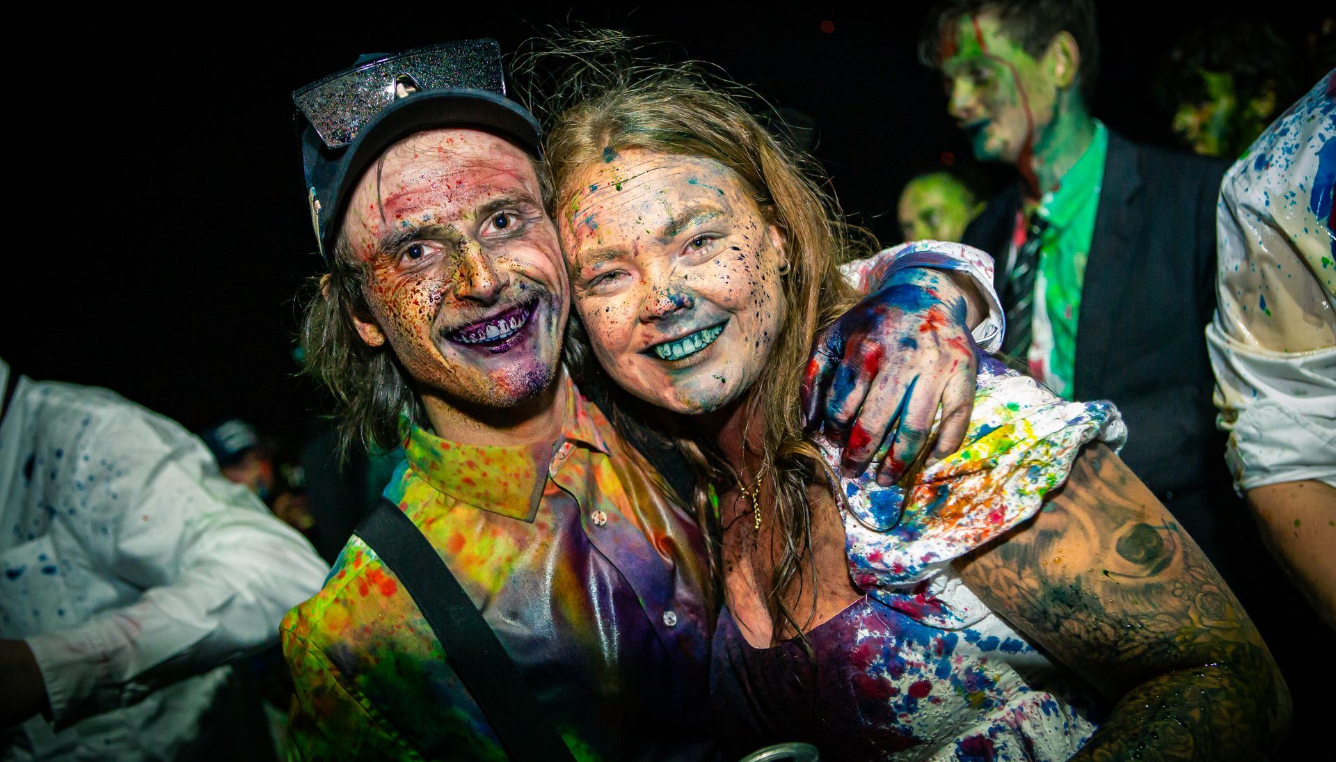 A man and a woman covered in paint are posing for a picture