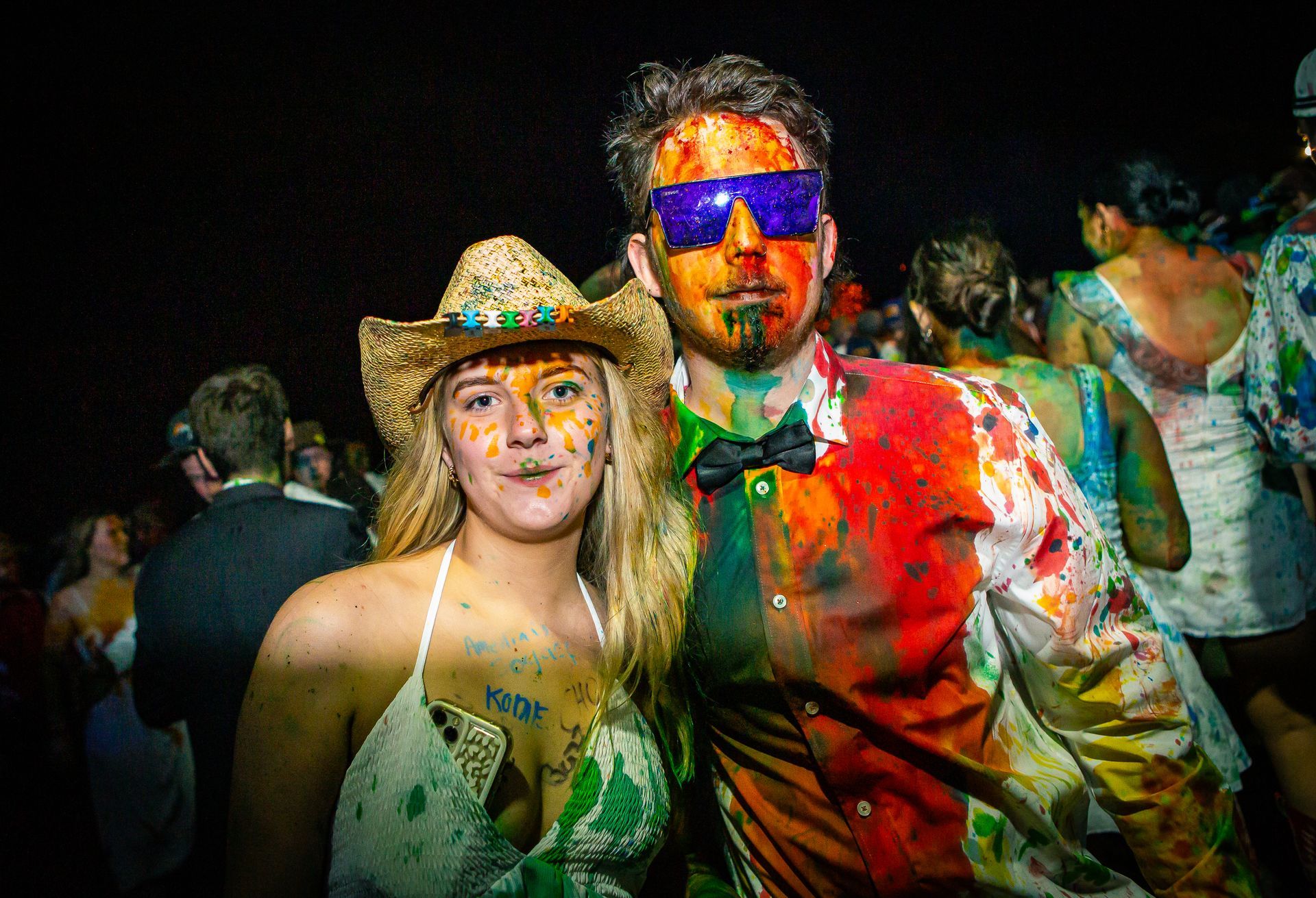 A man and a woman covered in paint pose for a picture