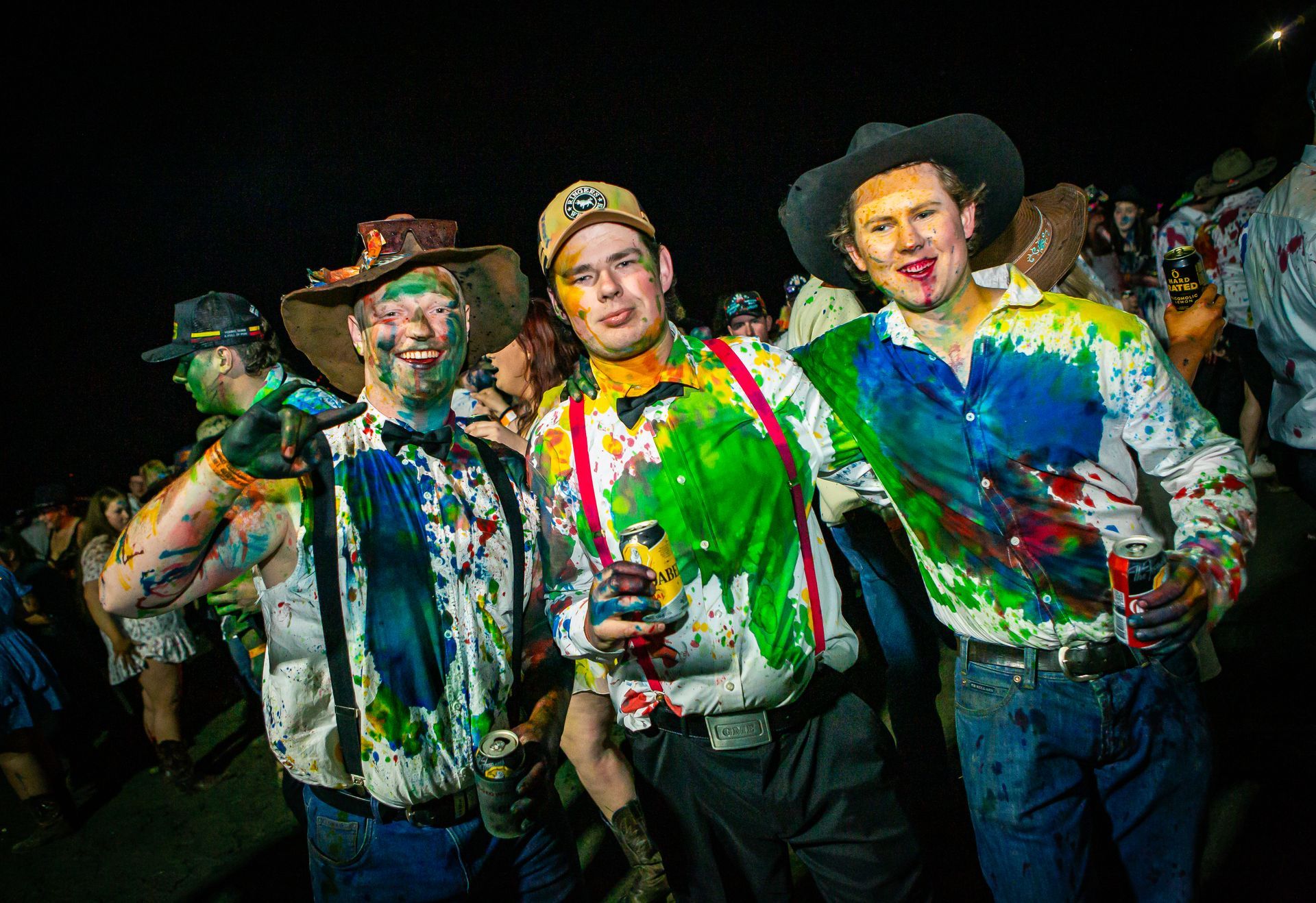 A group of men are covered in paint including one wearing a cowboy hat