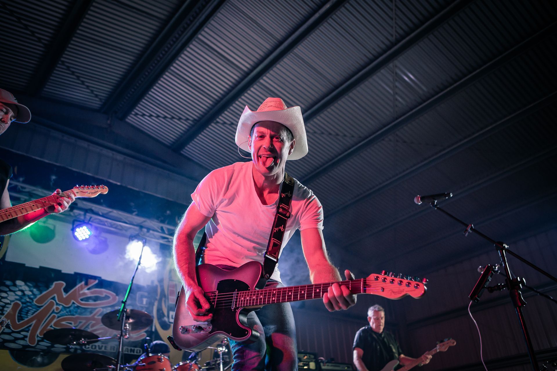 A man in a cowboy hat is playing a guitar on stage