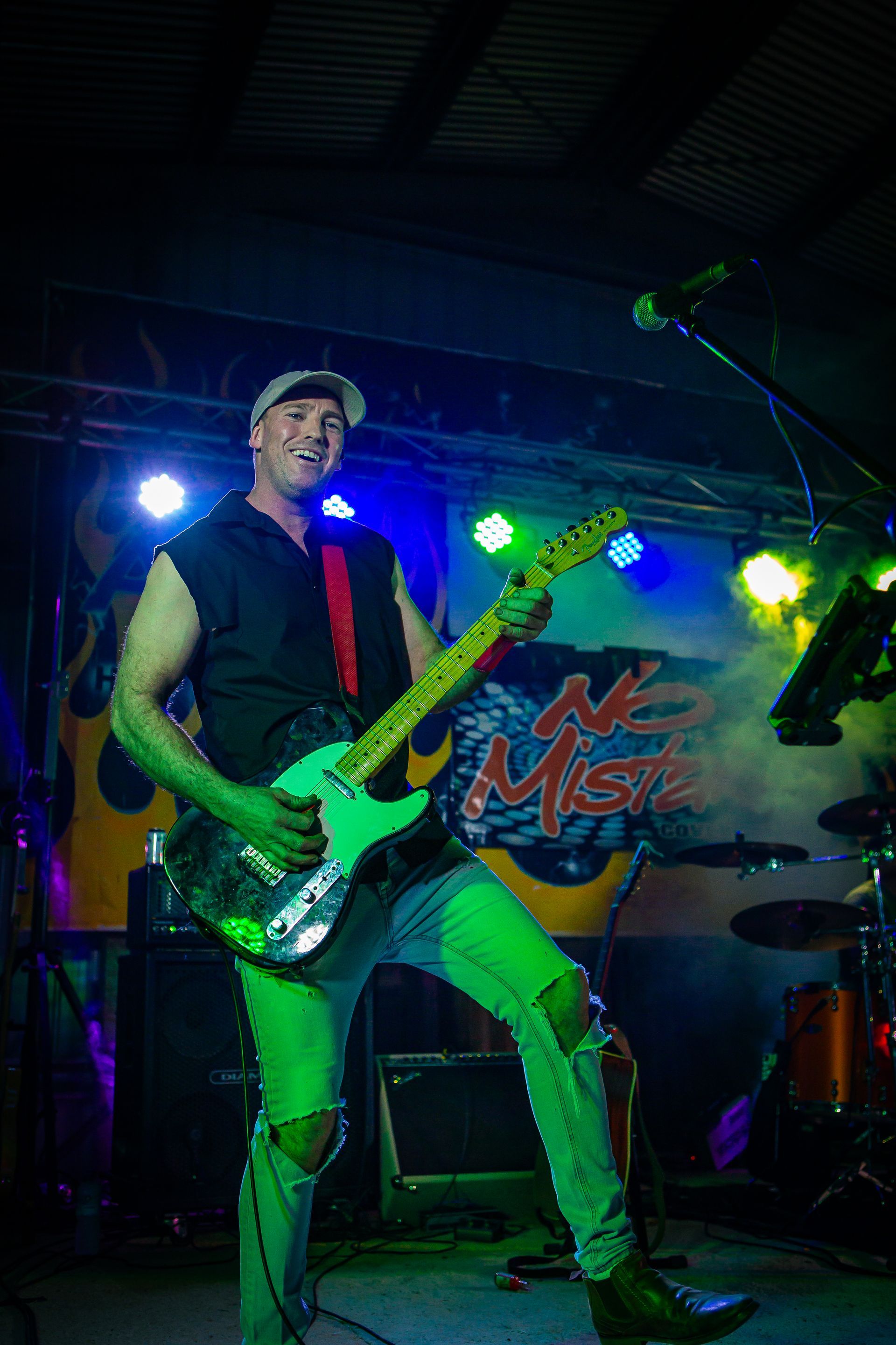 A man playing a guitar in front of a sign that says misfits