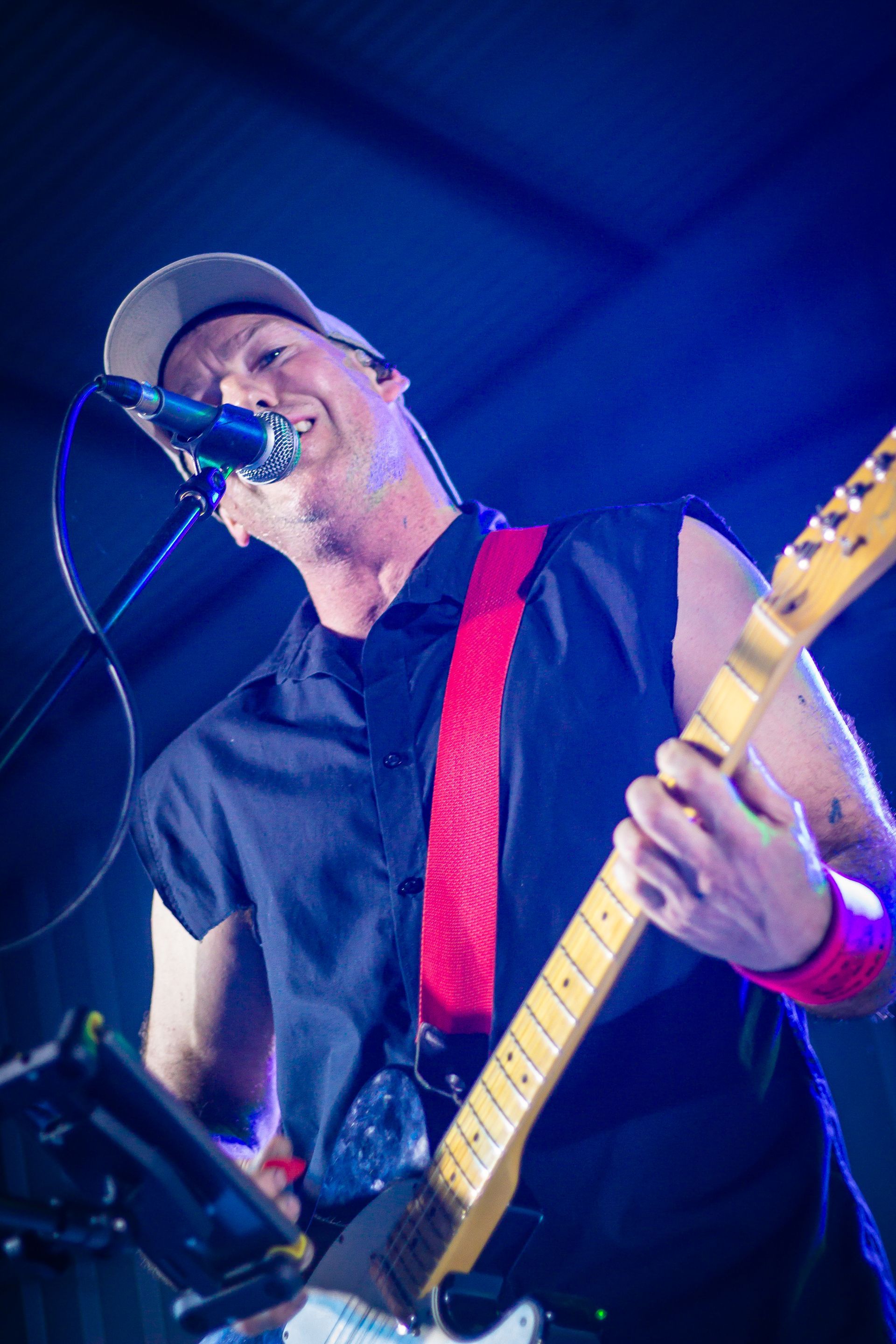 A man singing into a microphone while holding a guitar