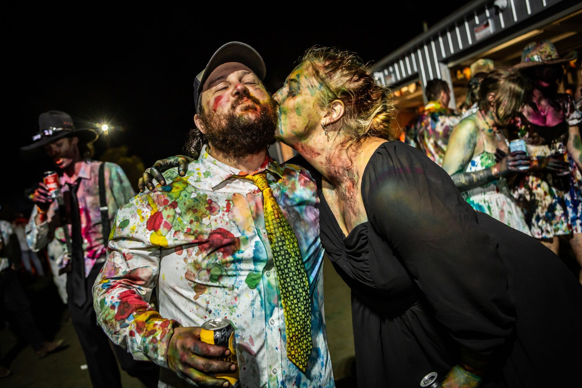 A woman is kissing a man who is covered in paint