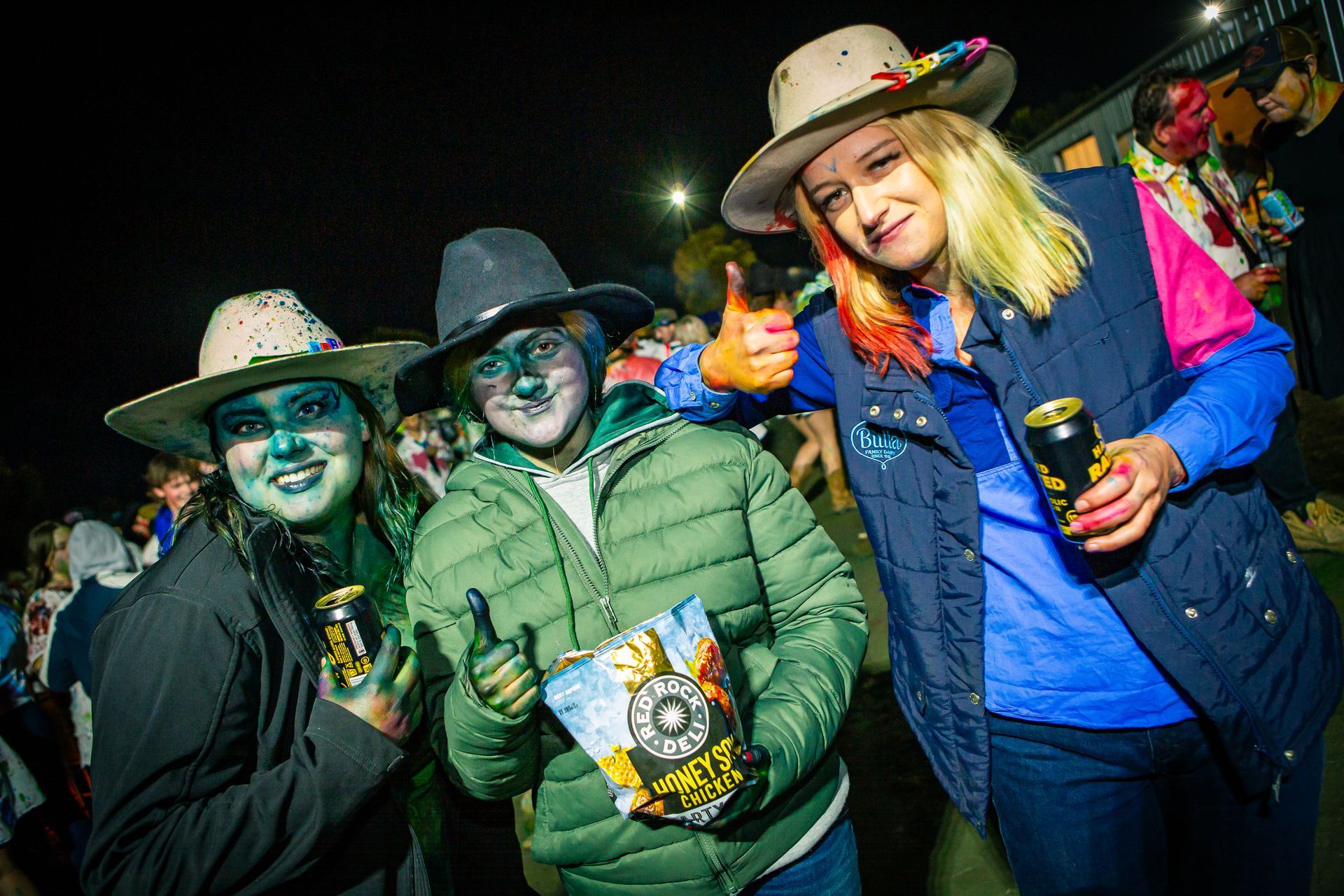 Three people are posing for a picture and one of them is holding a bag of potato chips