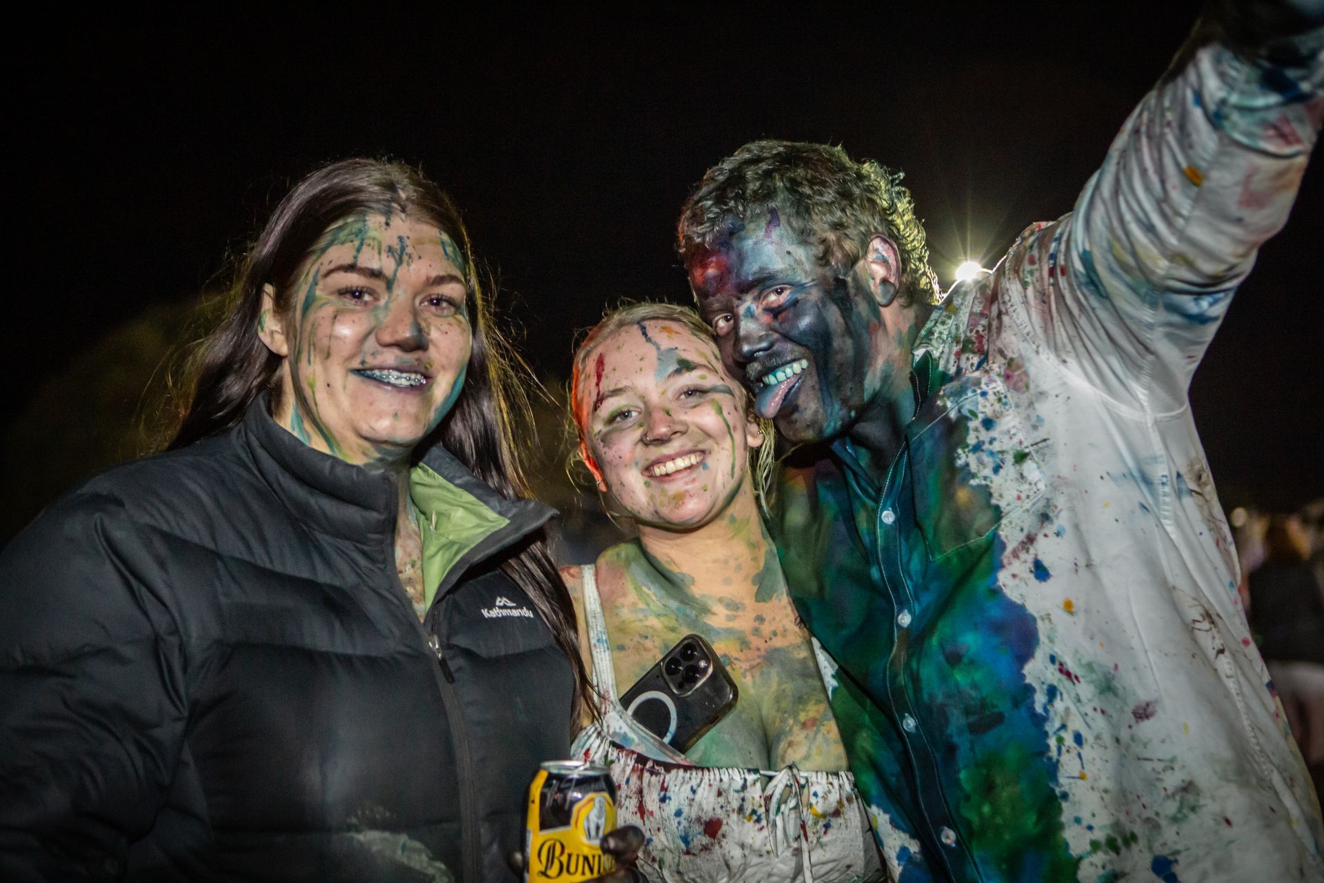 A man and two women are covered in paint and posing for a picture