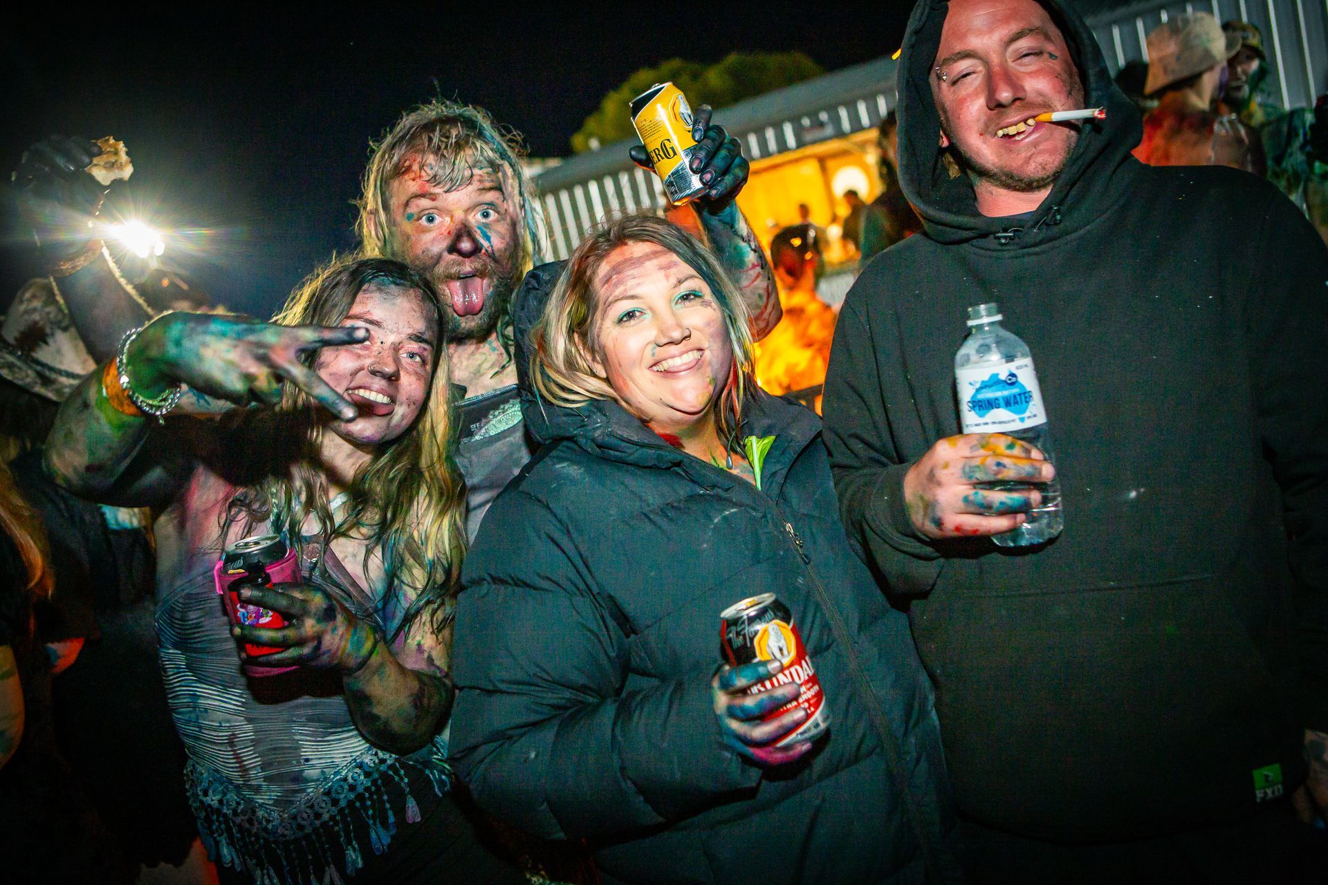 A group of people are posing for a picture and one of them is holding a bottle of aquafina water