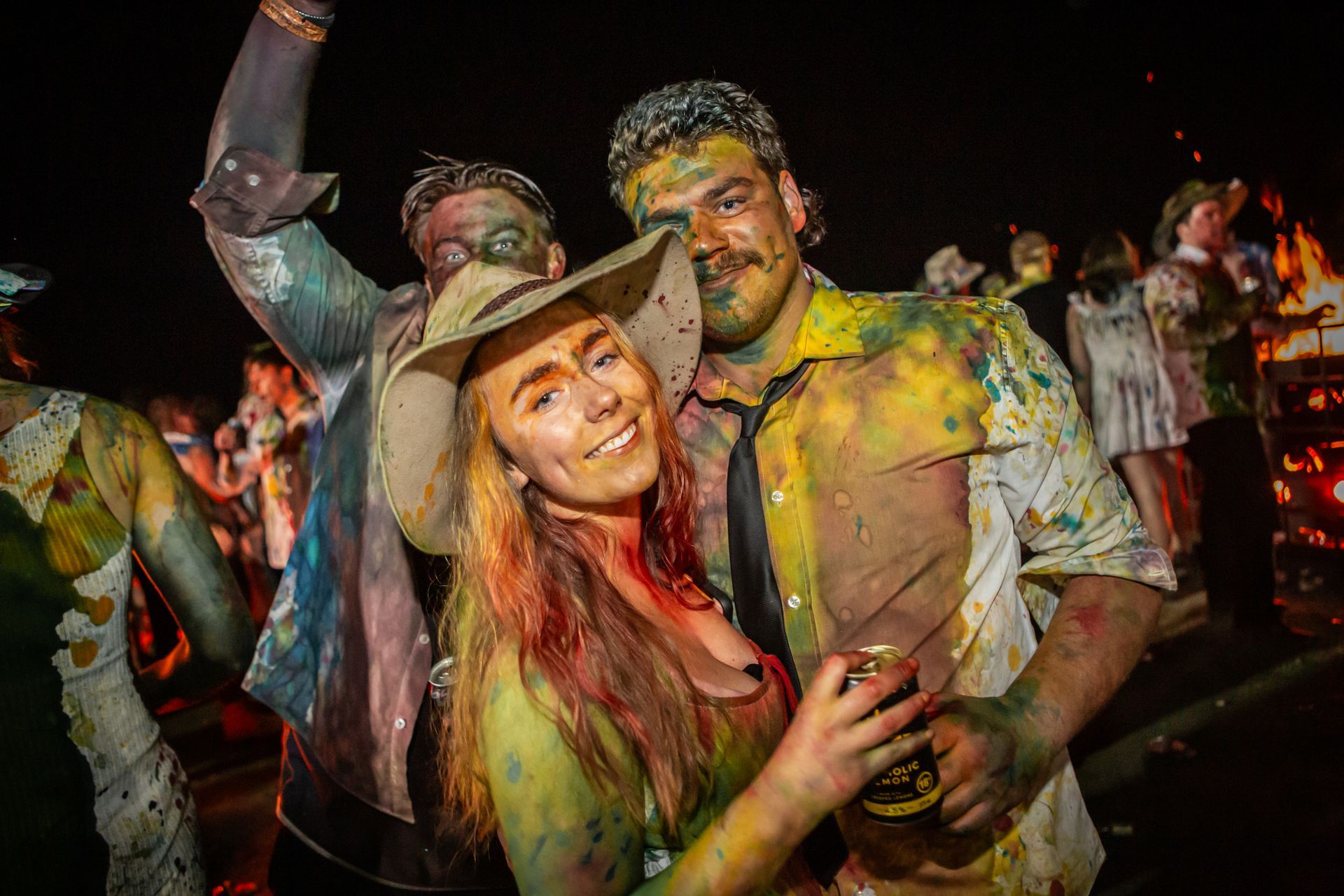 A man and a woman covered in paint pose for a picture