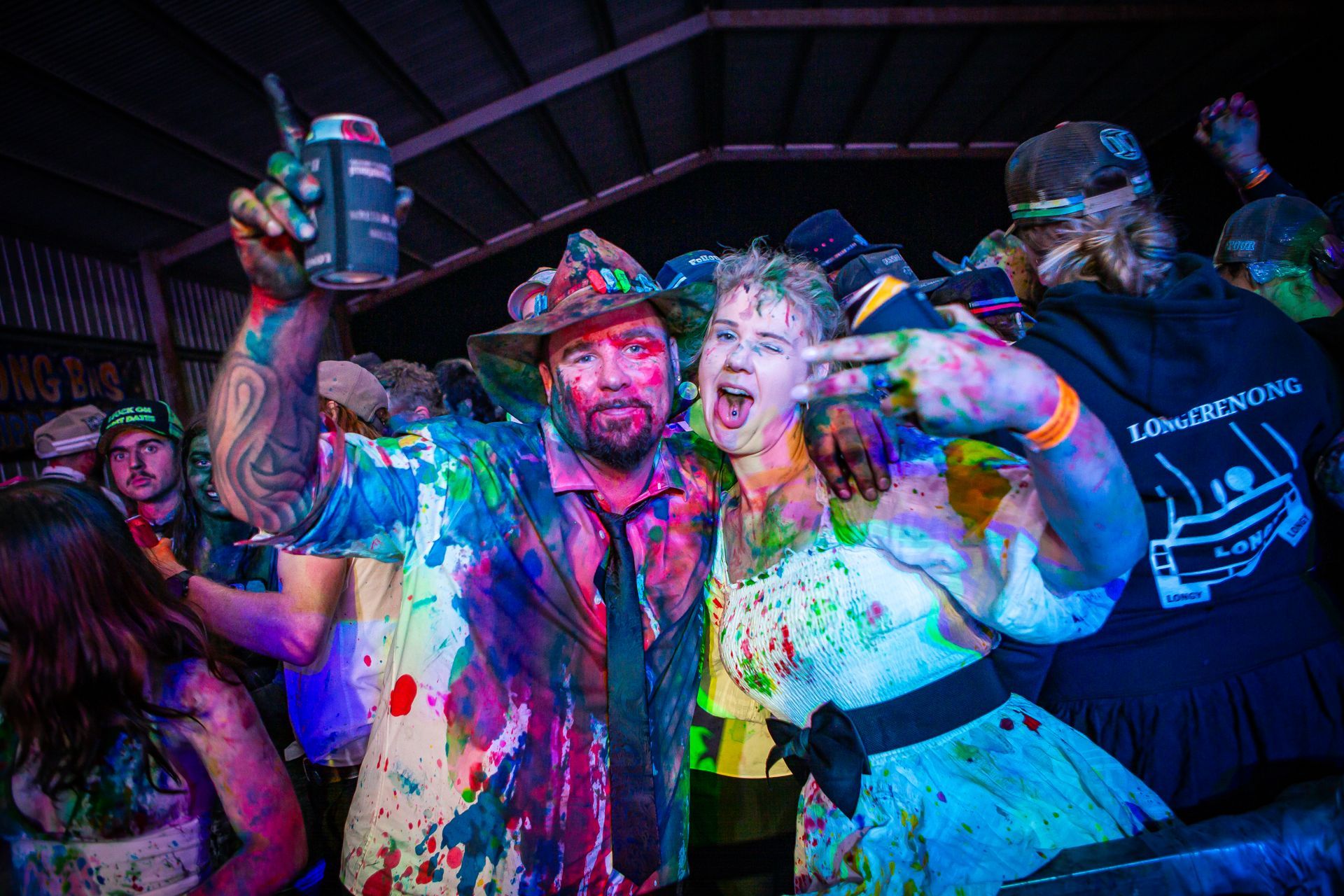 A man in a cowboy hat is holding a can of beer