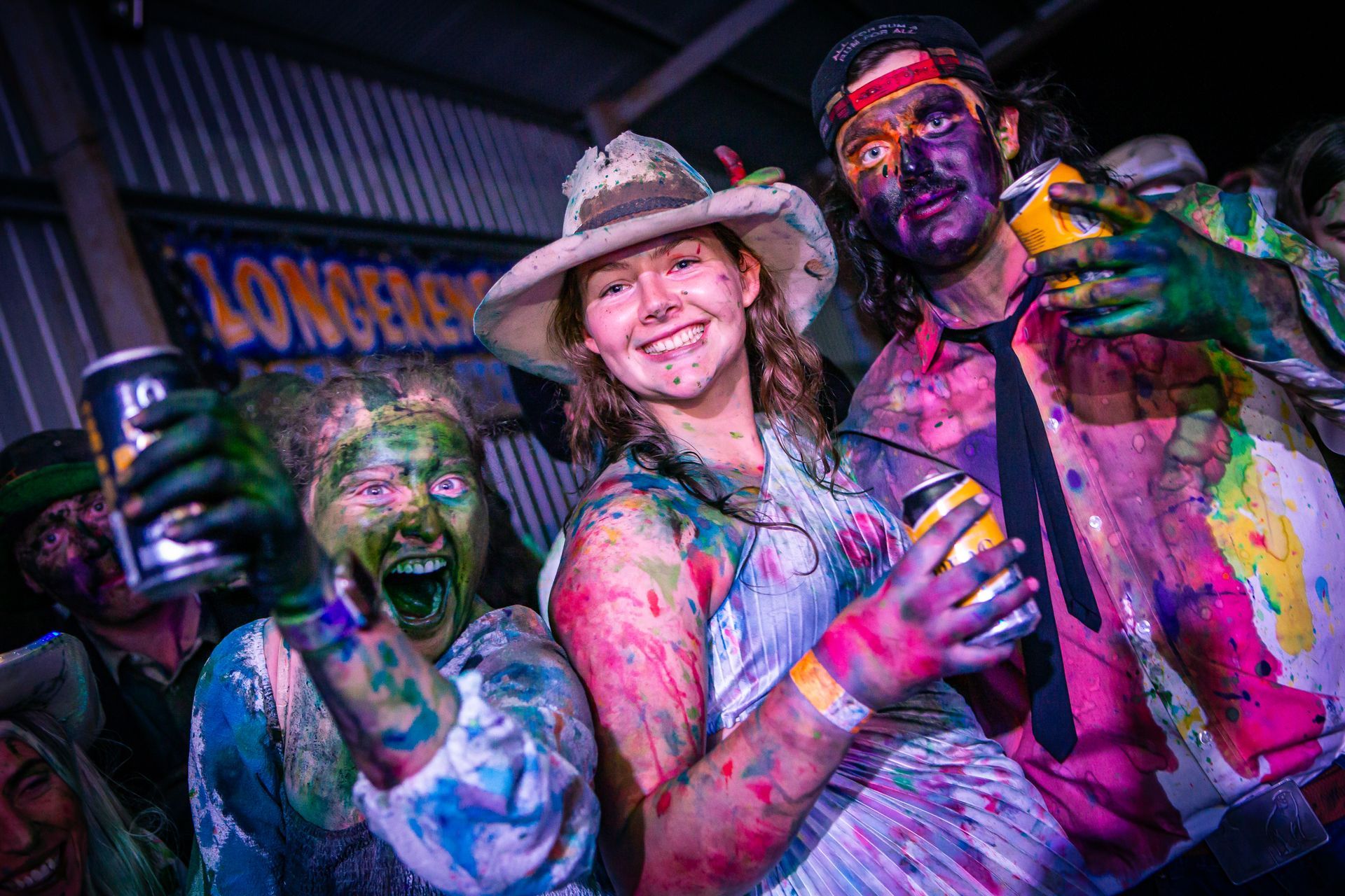 A group of people with paint on their faces are standing in front of a longhorn sign