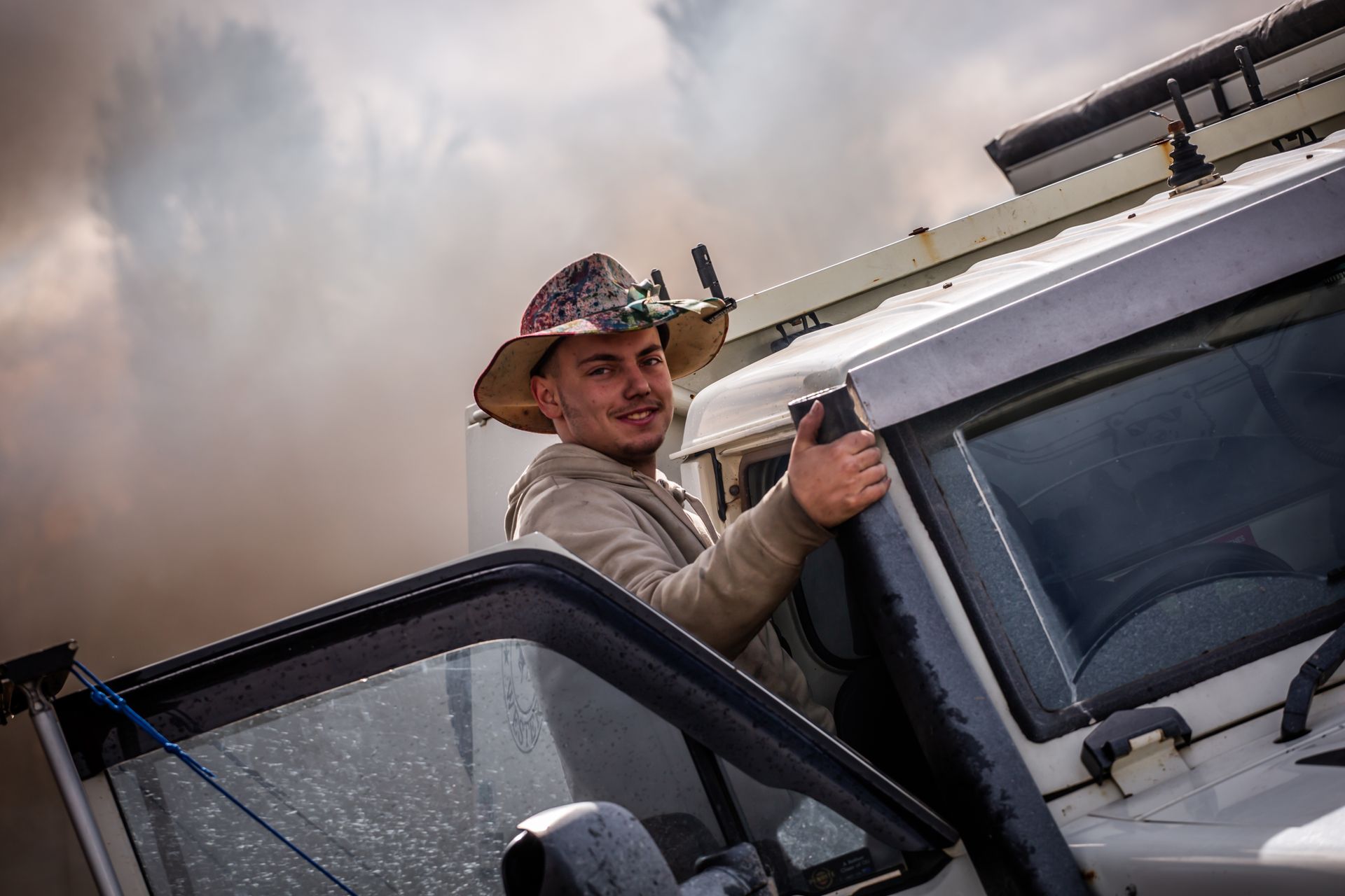 A man wearing a cowboy hat is leaning out of a car window