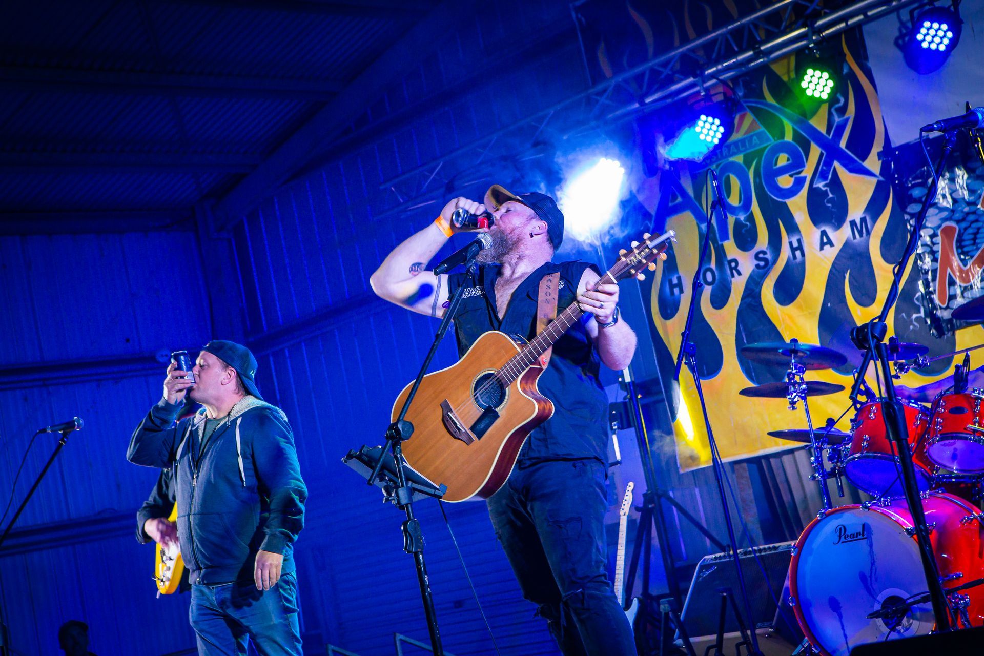 A man singing into a microphone while another man plays a guitar on stage